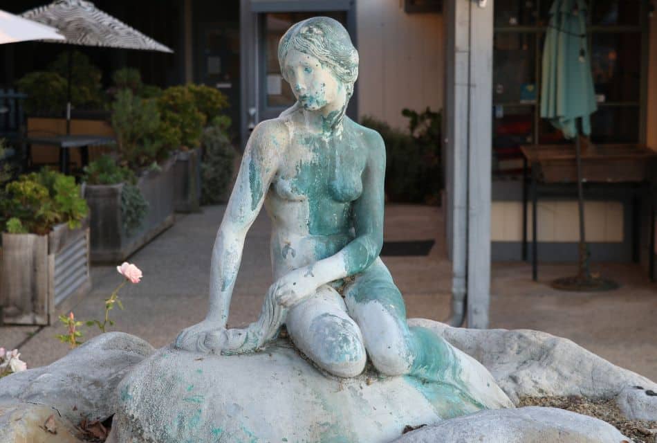 A large sculpture of a woman sitting on a rock outside a restaurant