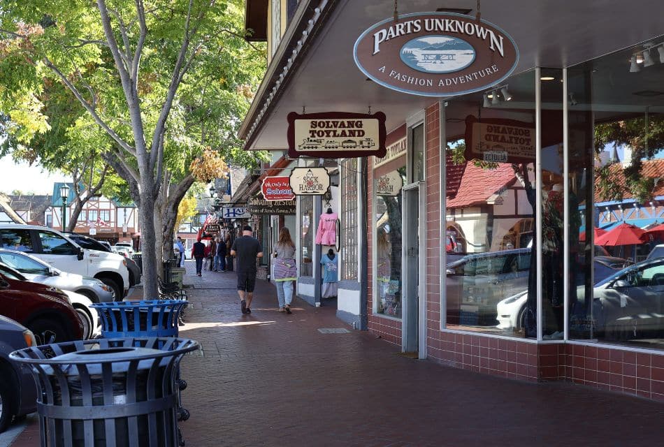 Quaint shopping street with brick path, shop signs hanging and people walking