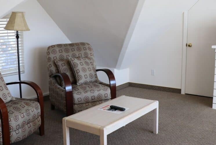 Sitting area with two plush chairs, table, tiled counter with microwave and a mini fridge