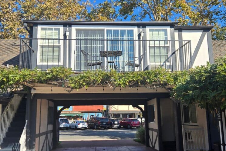 A small bedroom with windows over a balcony driveway through a white building