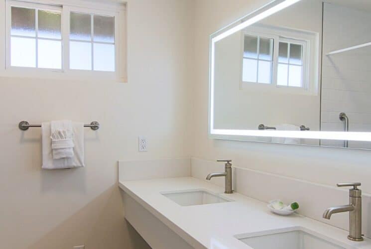 White bathroom with two sink vanity, large mirror and shower with curtain