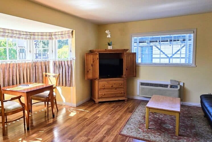 Spacious living room with breakfast nook with bay window, couch, table, TV and hardwood floors