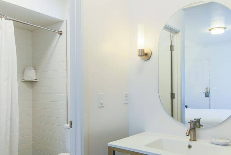 Bathroom with sink, oval mirror, sconces and shower with white curtain