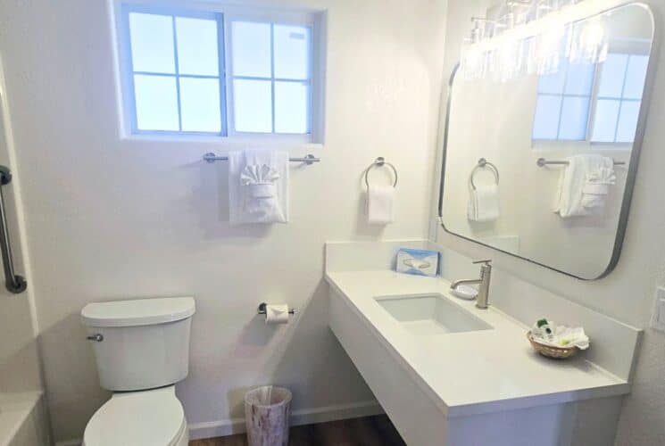 White bathroom with toilet, vanity, mirror and tub and shower with shower curtain