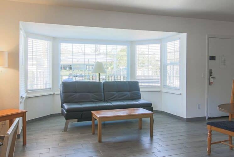 Living room of a suite with couch, coffee table, round table with two chairs, TV over writing desk with chair