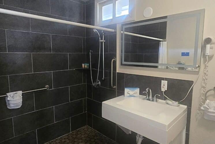 Bathroom with large tiled shower, single sink with mirror