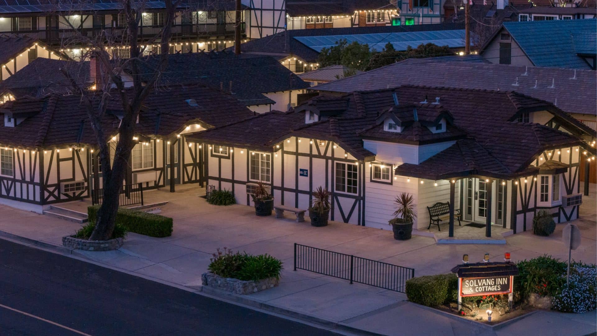 A complex of white and brown buildings with an inn, a hotel and cottages, all lit up at night with white liights