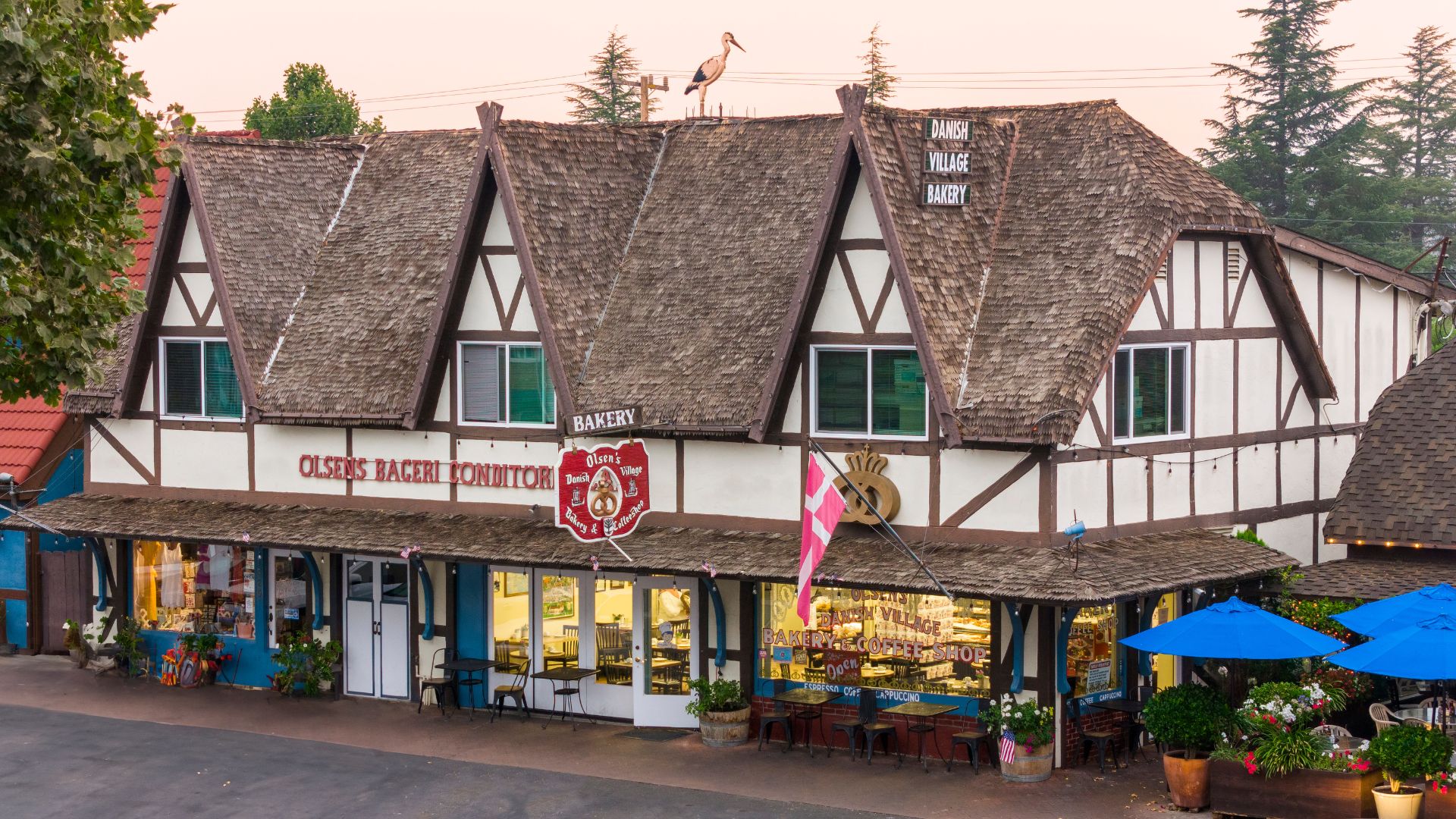 Large Bavarian style bakery shop with outside tables and chairs and patio umbrellas