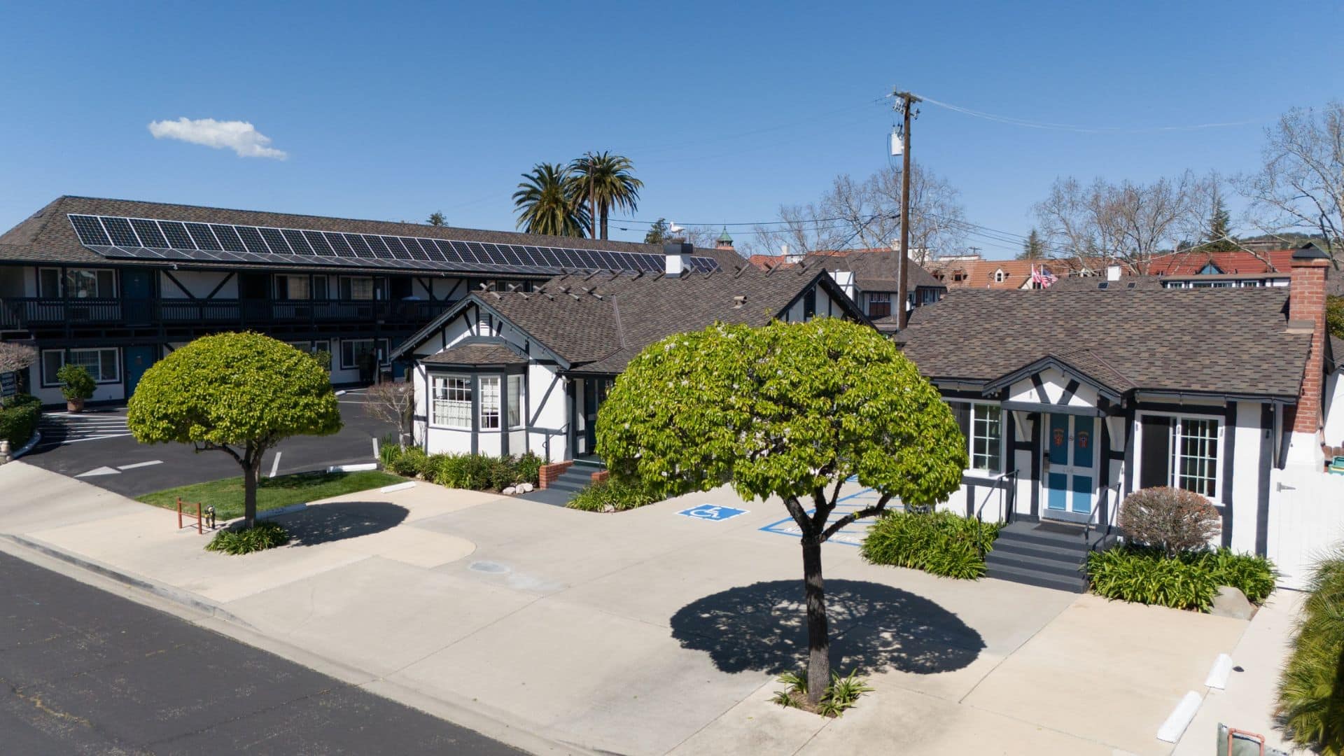 Outside street view of two cottages and a large hotel block of rooms